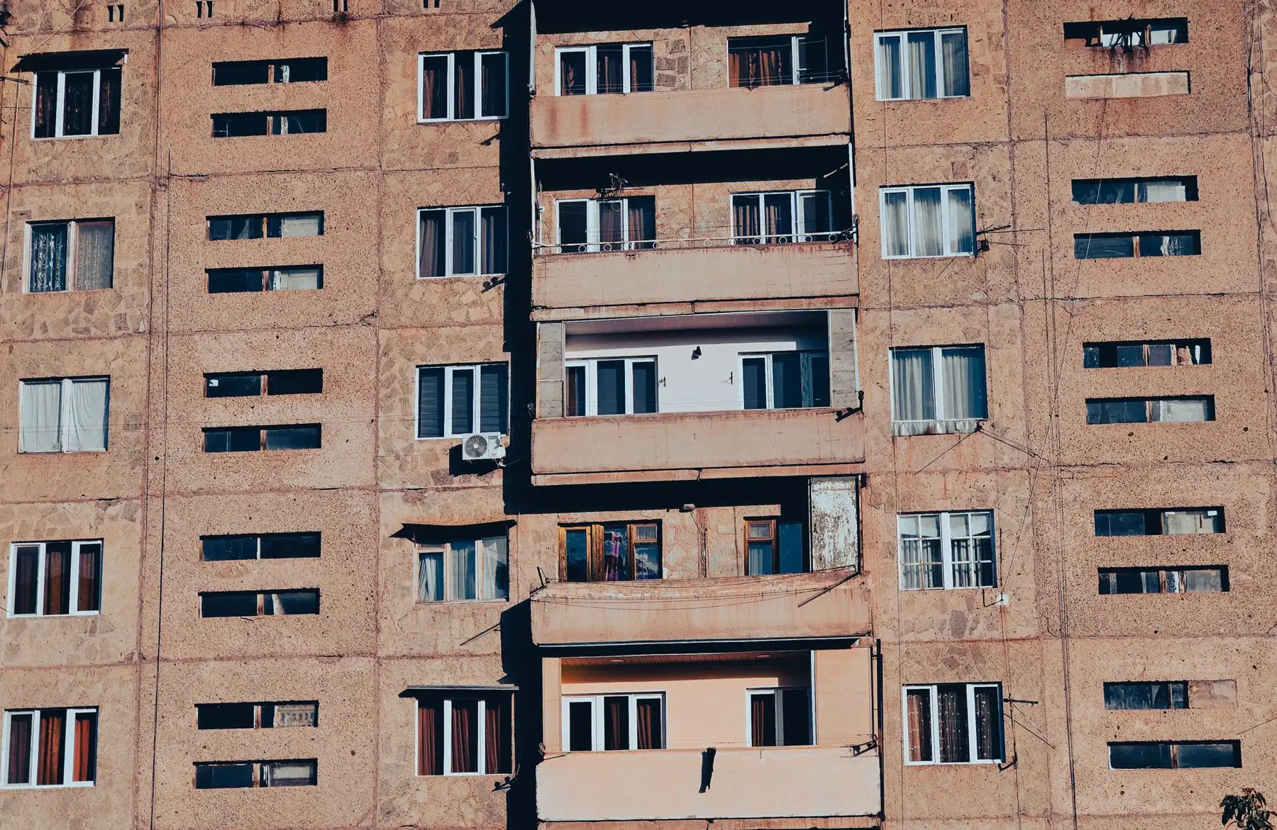 Senos statybos daugiabučio fasadas su balkonais ir langų eilėmis